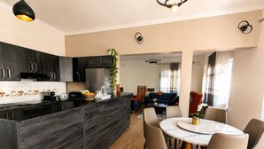 Una cocina moderna con armarios oscuros, una isla central y un comedor con una mesa redonda y sillas.