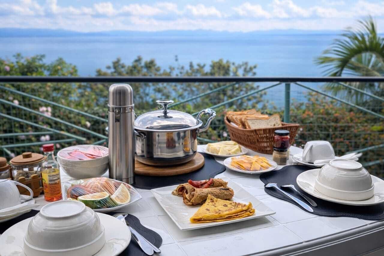 Desayuno con vista al mar, que incluye una tetera, platos y diversos alimentos.