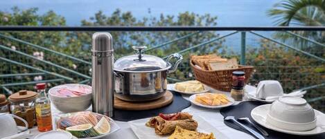 Desayuno con vista al mar, que incluye una tetera, platos y diversos alimentos.