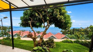 Un espacio al aire libre cubierto con vista al mar, un árbol y un edificio con tejados rojos.