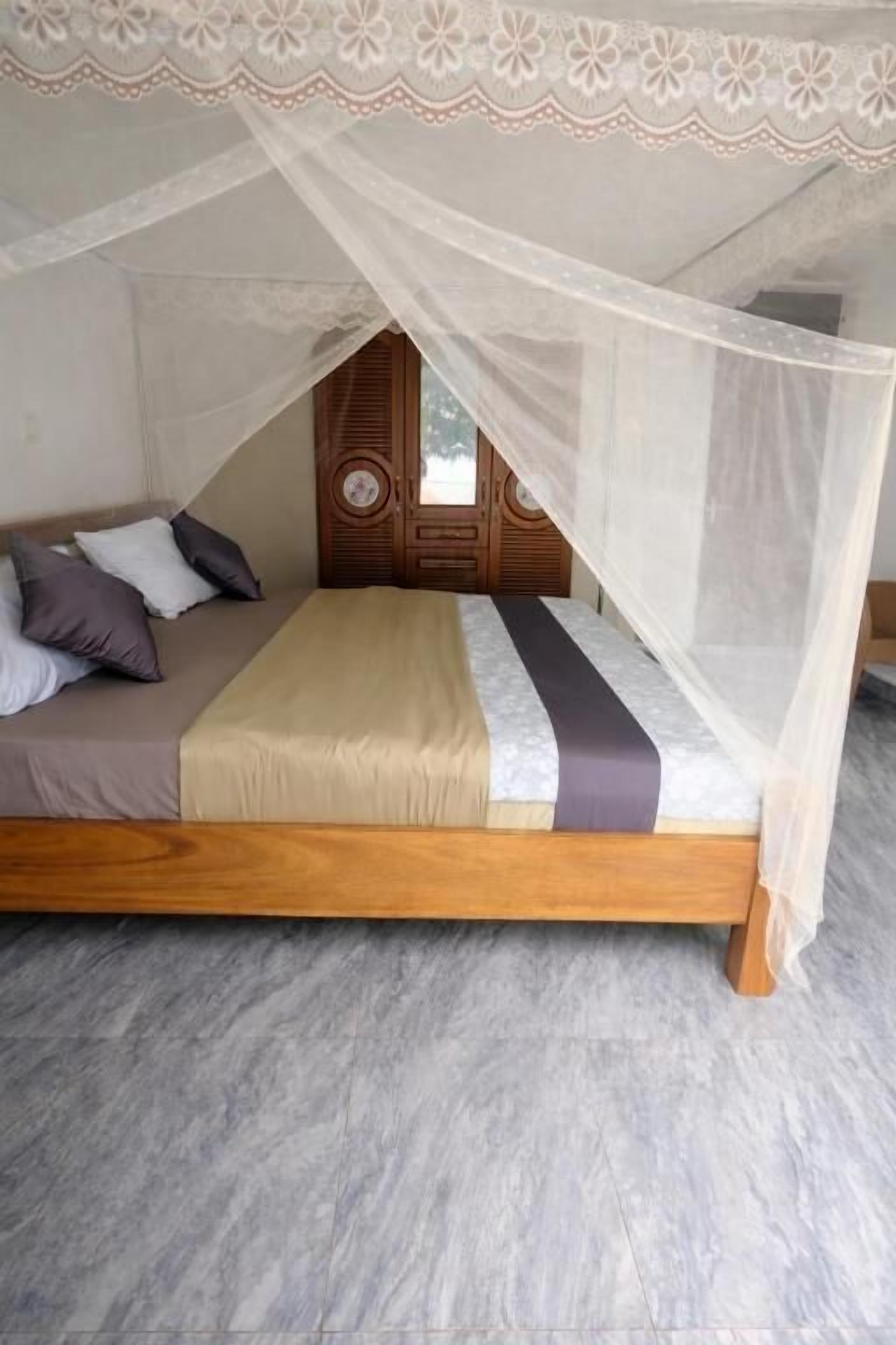 Un lit à baldaquin, une porte en bois et un sol carrelé.