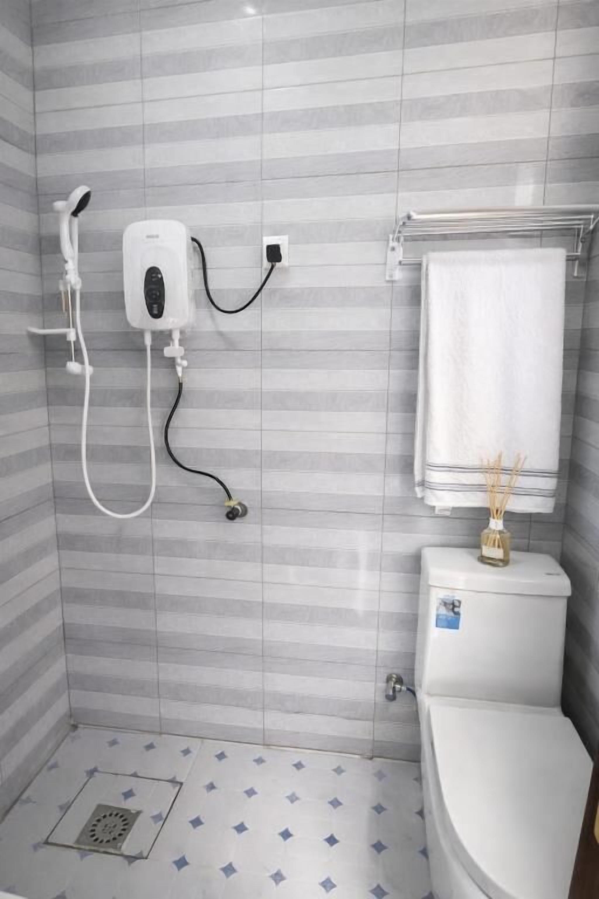 A bathroom with a shower, toilet, and a towel rack.