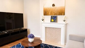 Un salón con televisión, chimenea y una alfombra azul estampada.