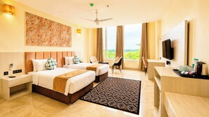A hotel room with two beds, a desk, a chair, a TV, and a large window with a view. - Yashshree Namdang Premier Hotel & Banquet (Margherita)