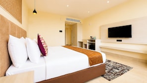 A modern hotel room with a large bed, a flat-screen TV, a wardrobe, and a desk area.