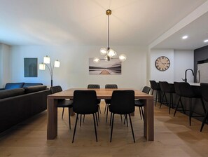 A modern dining area with a wooden table, black chairs, and a pendant light. - 200-214 - Level 2 - 2BD, 6 people (Beaupré)