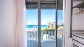 Uma varanda com vista para o mar, cadeiras e mesa brancos.