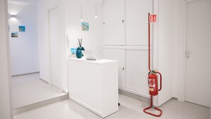 Um saguão de hotel moderno, com um balcão de recepção, um extintor de incêndio e uma porta.