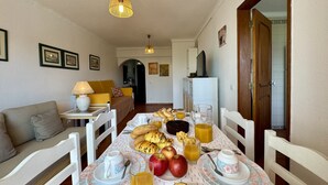 Zona de dinar amb taula preparada per esmorzar, incloent pa, pomes i suc.