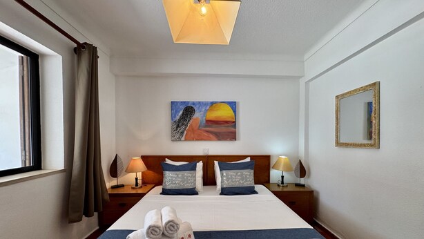 Habitació d'hotel amb un llit, un quadre, una finestra i un mirall.