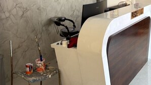 A reception desk with a 'RECEPTION' sign, a wall-mounted air conditioner, and four clocks. - Hotel Runway (Vadodara)