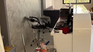 A room with a marble wall, a desk with a computer, a chair, and a window with a view of trees. - Hotel Runway (Vadodara)