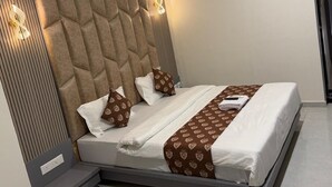 Una habitación de hotel moderna con una cama grande, un cabecero con diseño geométrico, una mesita de noche y un equipo de aire acondicionado.