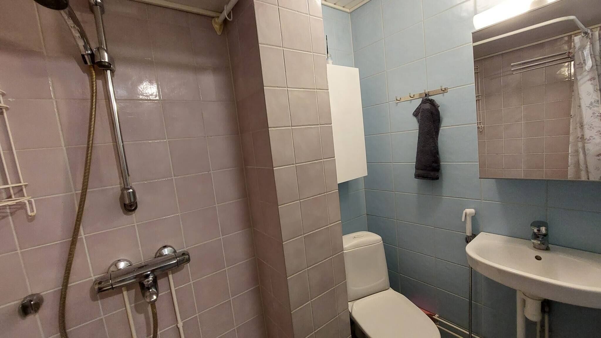 A bathroom with a shower, toilet, sink, and towel rack.
