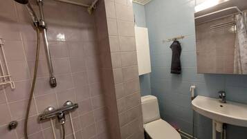 A bathroom with a shower, toilet, sink, and towel rack.