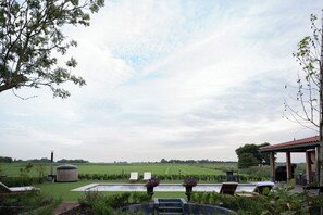 A pool area with lounge chairs, a pergola, and a view of a green field. - Luxurious farm stay with a pool and covered patio in the polder (Grootschermer)