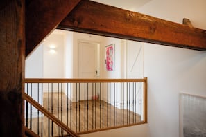 A wooden staircase with a railing, a white door, and a framed picture on the wall. - Luxurious farm stay with a pool and covered patio in the polder (Grootschermer)