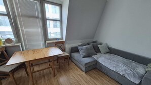 Un petit salon moderne avec une table en bois, un canapé gris et un radiateur.