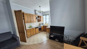 Une cuisine moderne avec des meubles en bois, un four encastré et un grand téléviseur à écran plat.