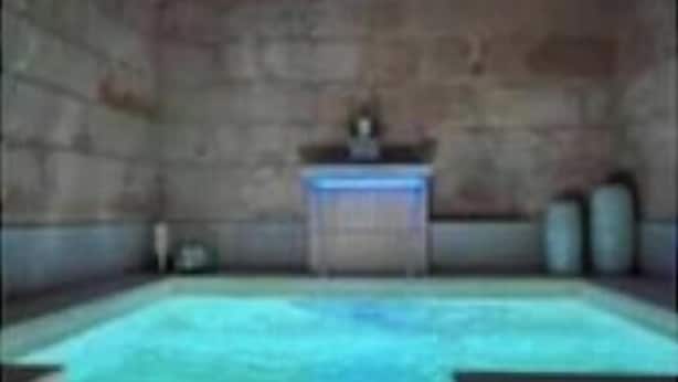 Une pièce aux murs de pierre, avec une piscine rectangulaire et une petite table.