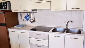 Ett kök med vita skåp, en dubbeldiskho och en mikrovågsugn.