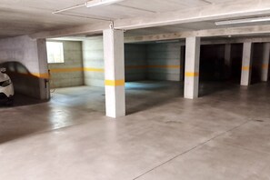 A parking garage with concrete pillars, yellow lines, and a concrete floor. - Cala Gonone, 2-Bedroom Apartment (Cala Gonone)
