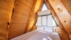 Un interior de madera con una cama, una ventana y un equipo de aire acondicionado.