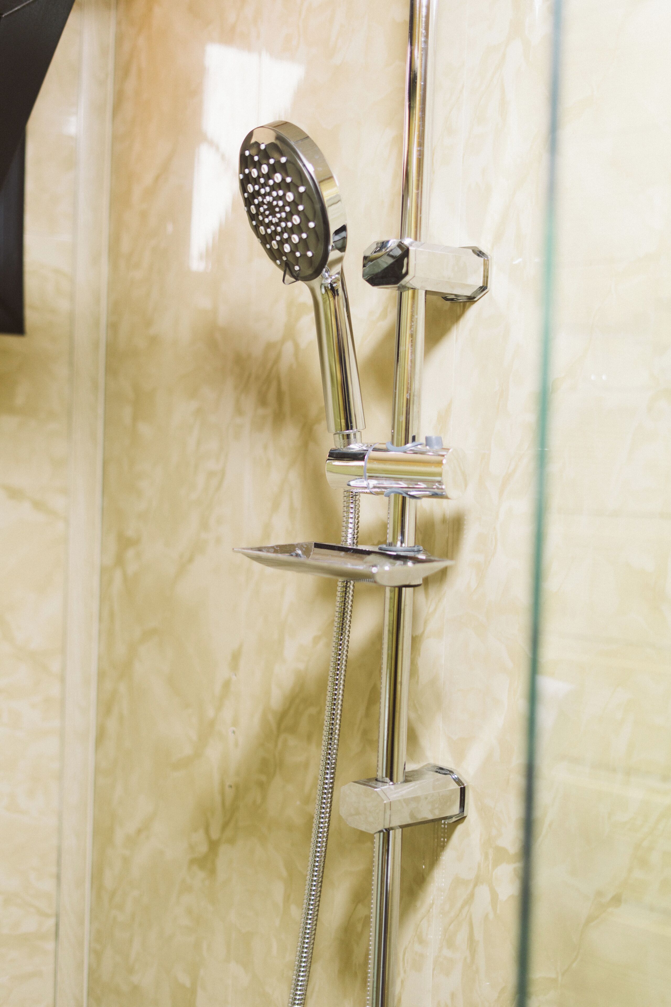A shower with a handheld showerhead and a wall-mounted control.