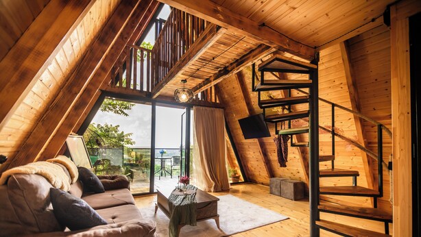 Un dormitorio estilo loft acogedor, con una escalera de madera, un sofá y una mesa de comedor.