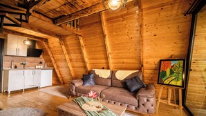 Un acogedor loft con techo de madera, un sofá, un cuadro y una kitchenette.