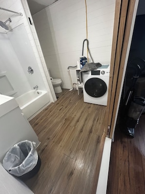 Une salle de bain avec une baignoire, des toilettes et un lave-linge.