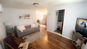 Un salon avec un canapé, un téléviseur et, au fond, un coin repas.
