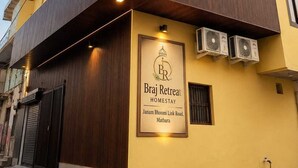 Een meerlaags gebouw met een bordje voor 'Braj Retreat Homestay' op de begane grond.