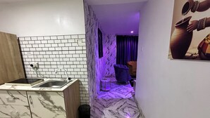 A compact kitchen with a marble countertop, a sink, and a tiled backsplash. - Desami Hotel (Lagos)