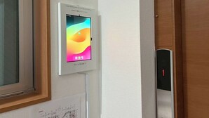 A wall-mounted device with a colorful display, a door with a numeric keypad, and a window with blinds. - YU'S HOUSE 2, a newly built property right next to JR Kamata Station (ootaku)