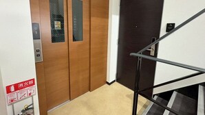 A wooden door with a fire extinguisher sign, a black door, and a metal handrail. - YU'S HOUSE 2, a newly built property right next to JR Kamata Station (ootaku)