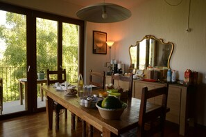 Zona pranzo con tavolo in legno, sedie, uno specchio grande e vista attraverso la porta vetrata.