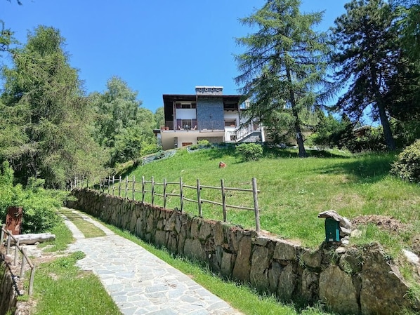 Un camino de piedra que lleva a un edificio moderno con un muro de piedra y una valla de madera.