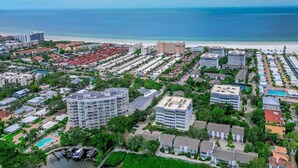 Eine Vogelperspektive auf ein Küstenwohngebiet mit Strandhäusern, einem Jachthafen und einem großen Hotelkomplex.