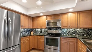 Eine moderne Küche mit Edelstahlgeräten, Holzschränken und einer Mosaik-Spritzwand.