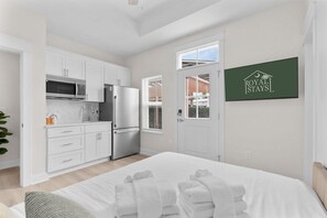 A modern hotel room with a kitchenette, a bed with white linens, and a view of the outside. - Dolce Vita - Near Beach & Boardwalk (Myrtle Beach)