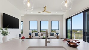 Eine moderne Küche mit einer zentralen Kochinsel, einem Deckenventilator und großen Fenstern mit Blick.