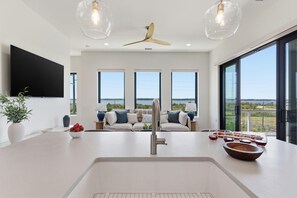 Eine moderne Küche mit einer zentralen Kochinsel, einem Deckenventilator und großen Fenstern mit Blick.