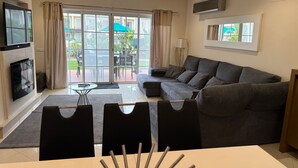 Ein Wohnzimmer mit einer Couch, einem Fernseher und einem Essbereich mit Stühlen.