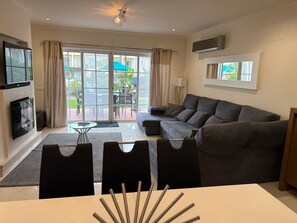 Ein Wohnzimmer mit einer Couch, einem Fernseher und einem Essbereich mit Stühlen.