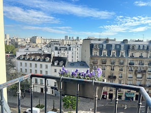 A cityscape with a variety of building styles, including a prominent building with a clock tower. - Charming studio apartment in Paris with a balcony, right near lines 1, 2, 6, 9, and the RER A! (Paris)