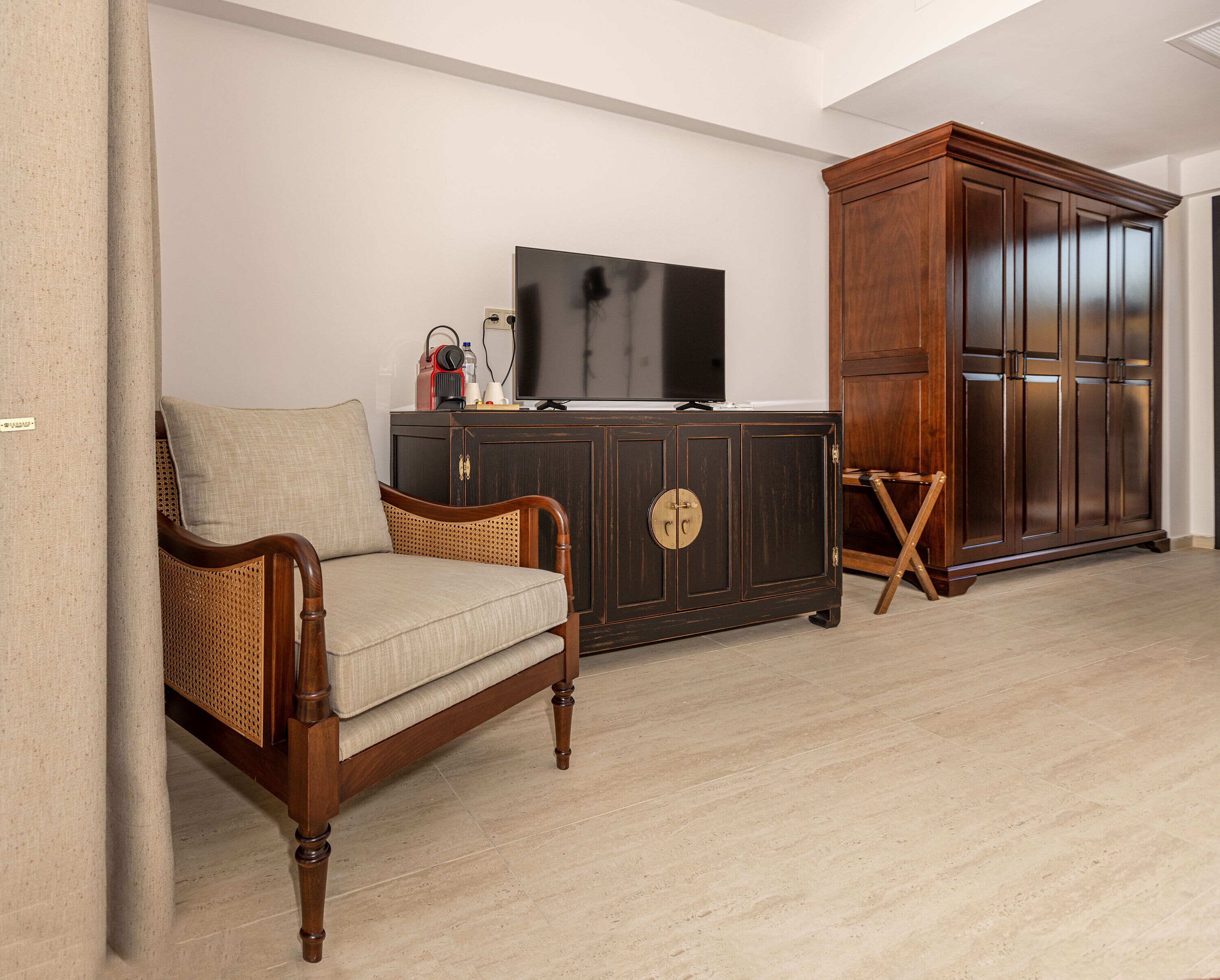 Ein Wohnzimmer mit Holzschrank, Fernseher und Korbstuhl.