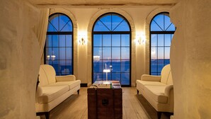 A room with three arched windows, a sofa, a coffee table, and a lamp. - Hotel Jirasol (Çeşme)