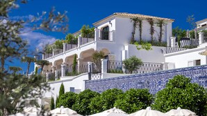 A white building with blue-tiled walls, balconies, and white umbrellas. - Hotel Jirasol (Çeşme)