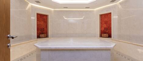 A modern bathroom with a central marble sink, recessed lighting, and decorative tiles.